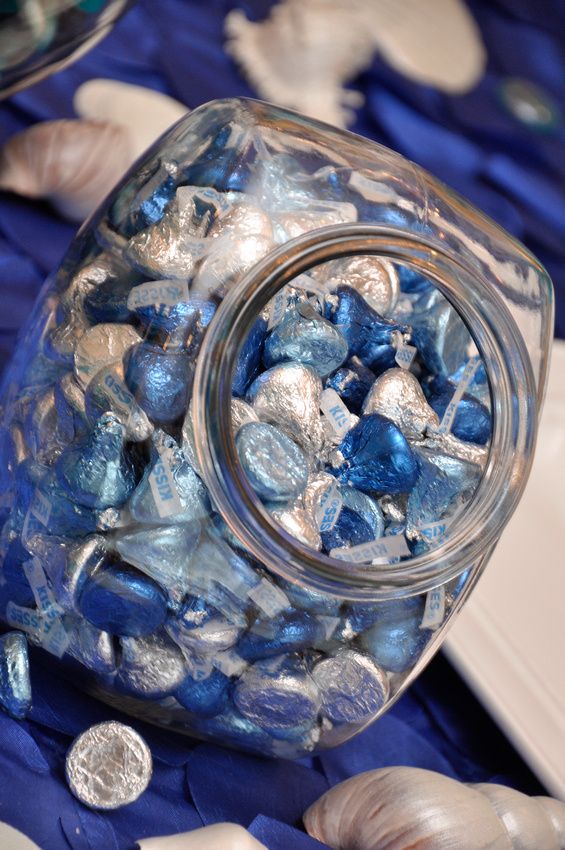 a jar filled with blue and silver candies on top of a purple table cloth