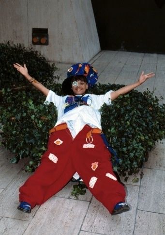 a young boy dressed in red and white poses for the camera with his arms outstretched