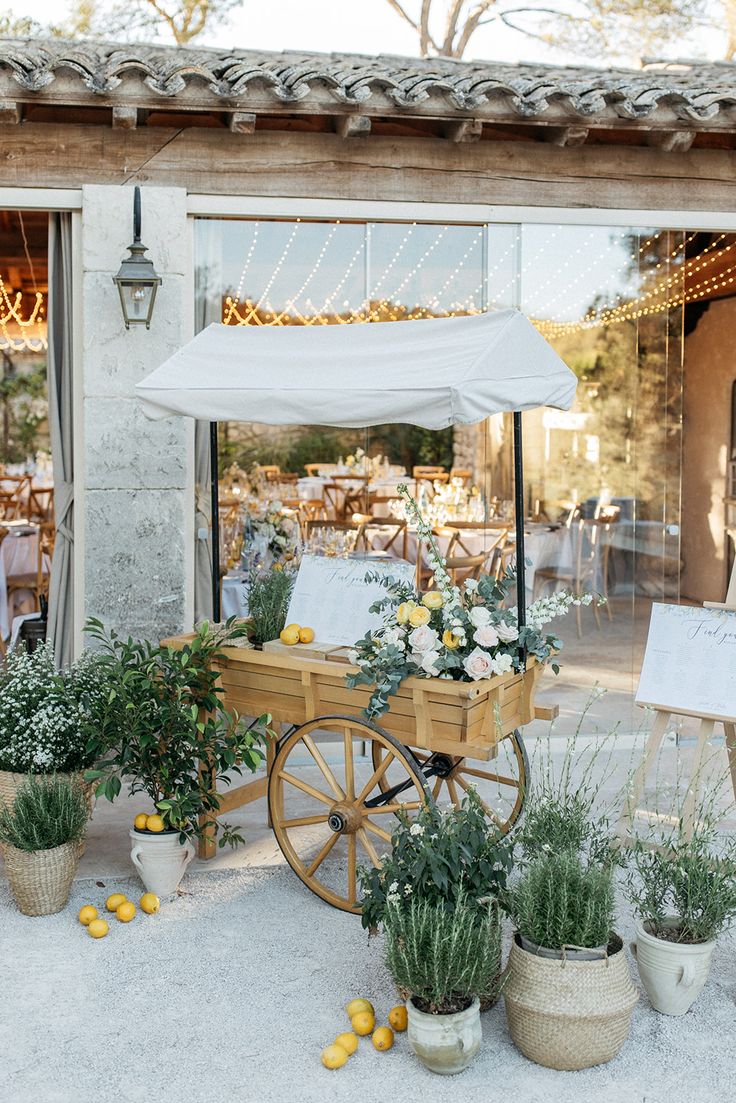 an old fashioned wagon with flowers and greenery in front of a building that is open to the public