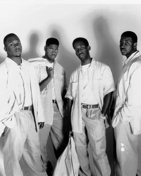 four men are posing for a black and white photo with their hands on their hipss