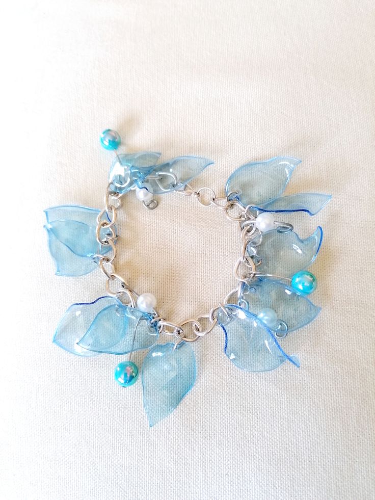 a bracelet with blue glass flowers and pearls on a silver chain, sitting on a white surface