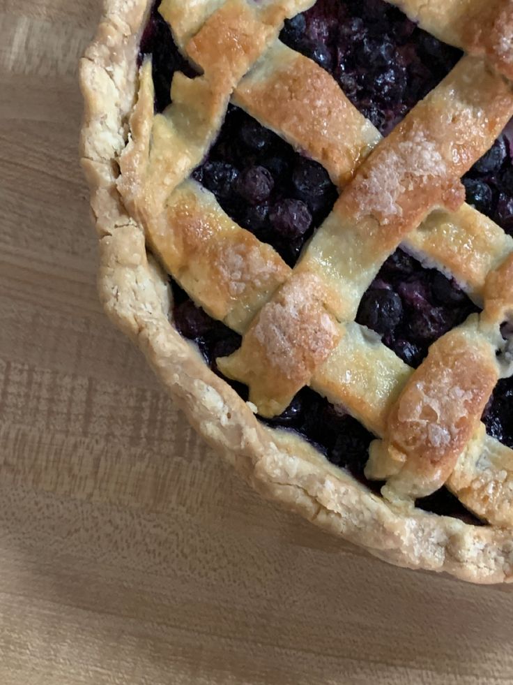 a blueberry pie sitting on top of a wooden table