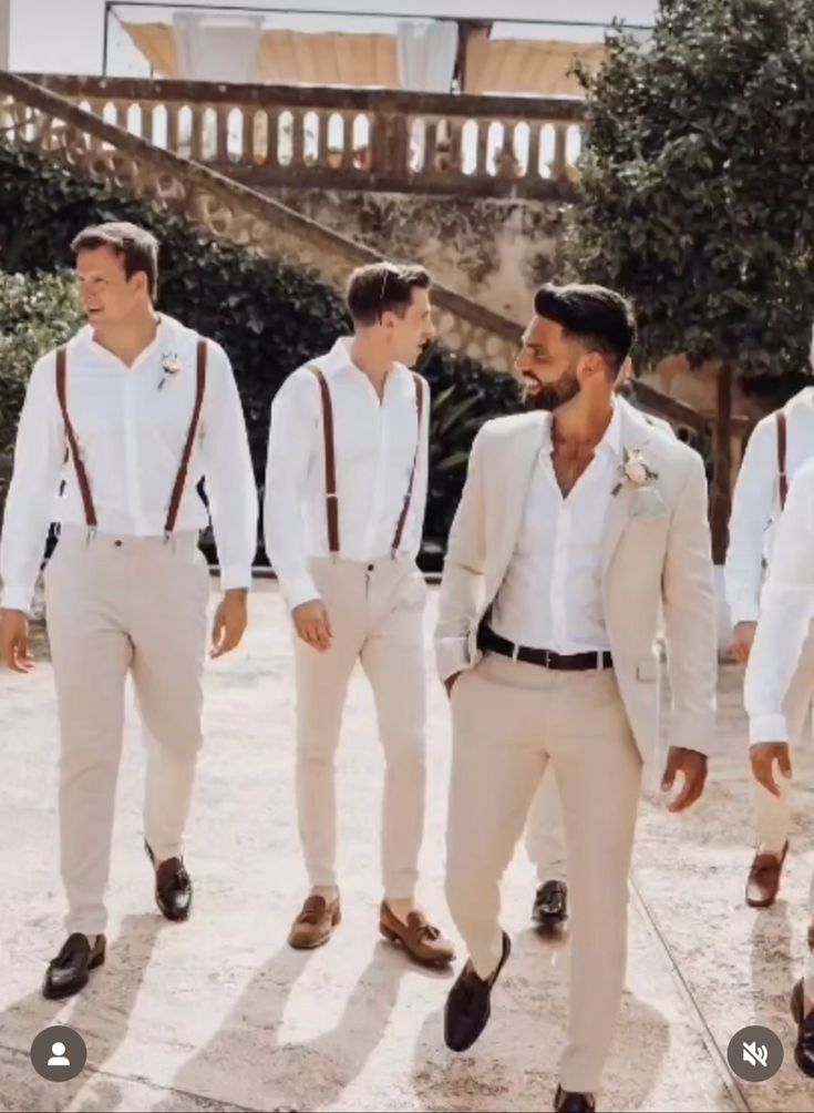 a group of men standing next to each other wearing white suits and ties with brown suspenders