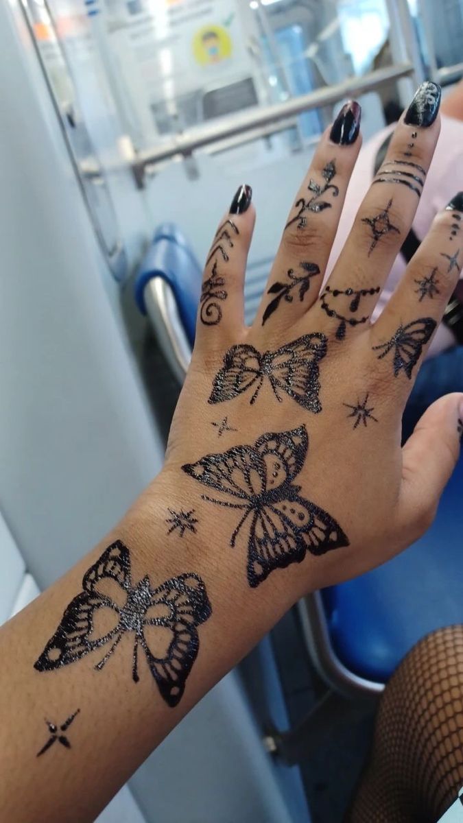 a woman's hand with tattoos and butterflies on her left arm, sitting in a bus