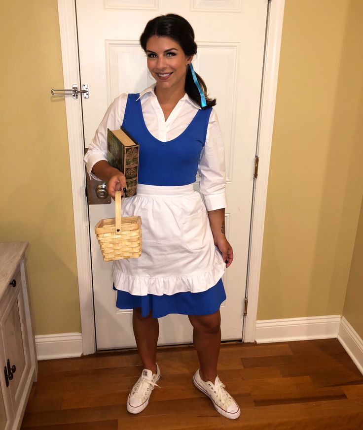 a woman in a blue and white dress is holding a basket while standing next to a door