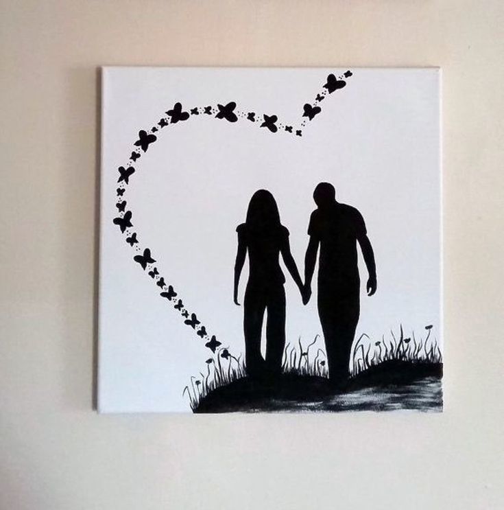 a couple holding hands with butterflies in the shape of a heart on a white wall