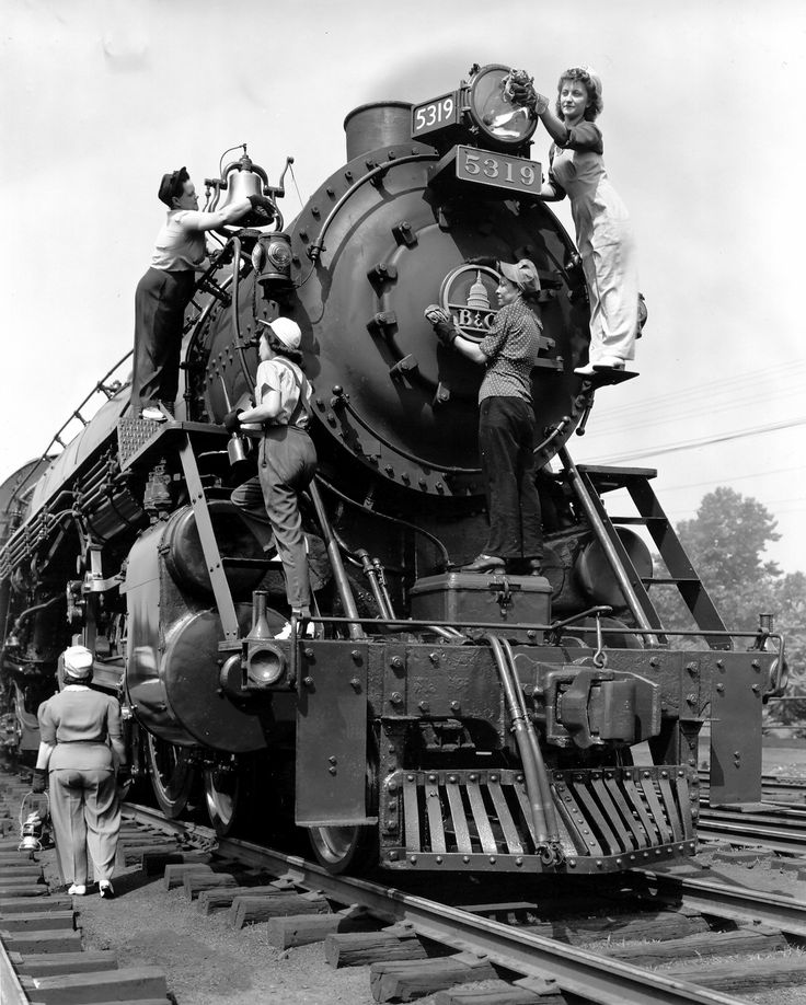 an old black and white photo of people on top of a train engine that is being worked on