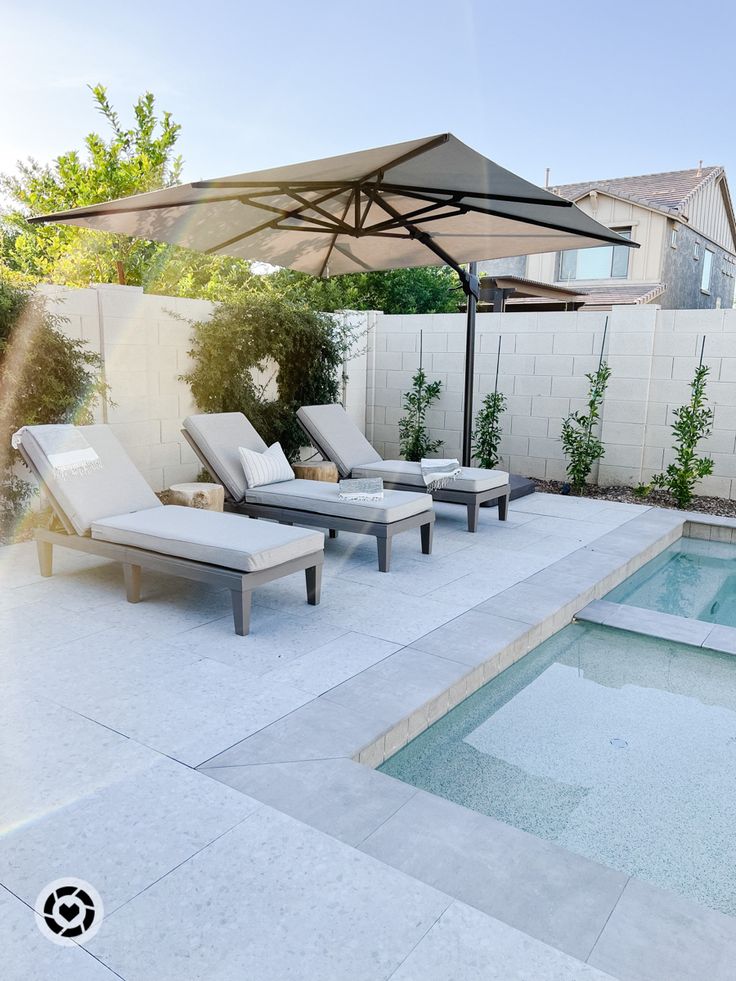 an outdoor pool with lounge chairs and an umbrella