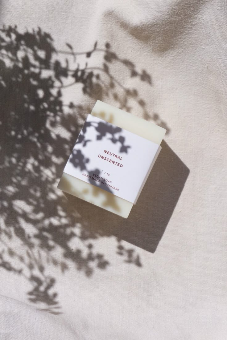 a soap bar sitting on top of a white sheet next to a tree branch with its shadow