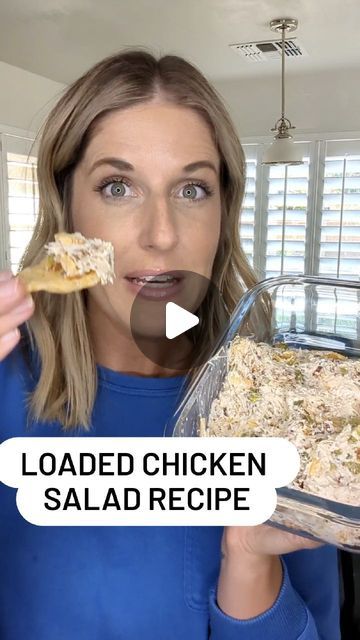 a woman is holding a chicken salad in her hand and looking surprised at the camera