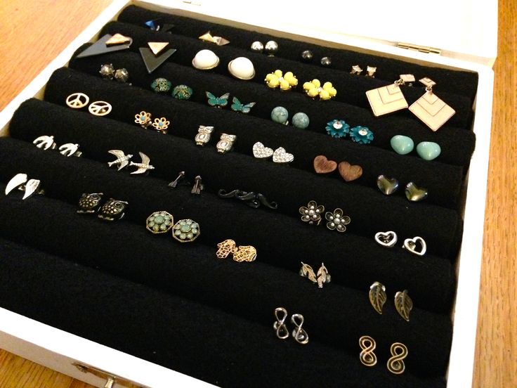 an open drawer with several pairs of earrings in it on top of a wooden table