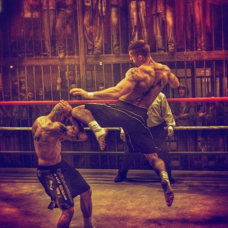 two men in the middle of a boxing ring, one kicking another with his leg