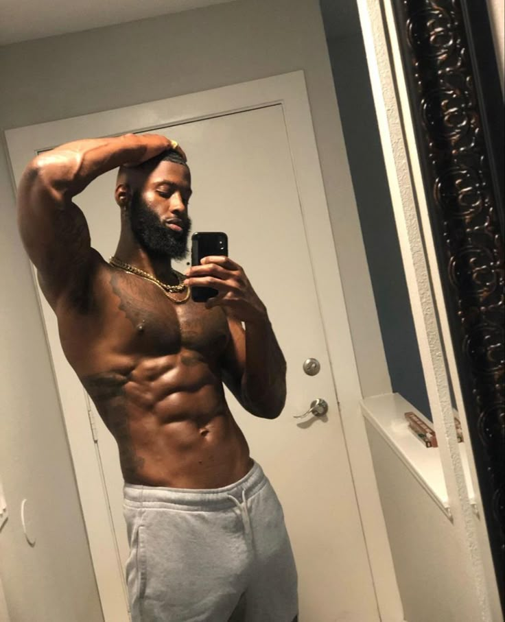 a shirtless man taking a selfie in front of a mirror with his cell phone