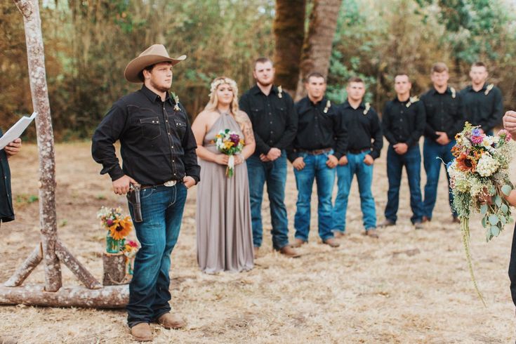 a man standing in front of a group of people wearing cowboy hats and holding flowers