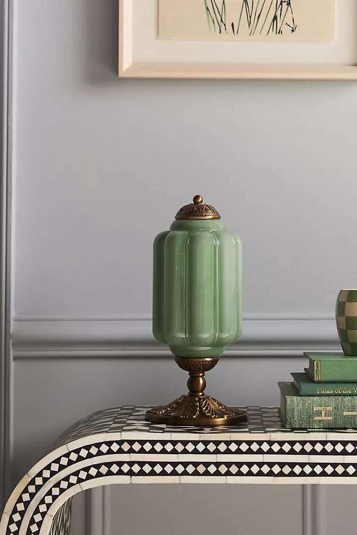 a green vase sitting on top of a table next to books and a coffee cup