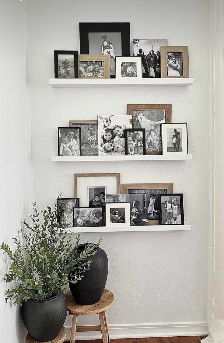 three white shelves with pictures and plants on them