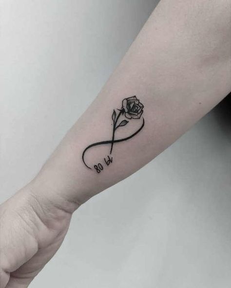 a black and white rose tattoo on the left inner arm, with an inscription that says go to heaven