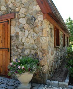 a potted plant sitting next to a stone building with wooden doors and windows on the side