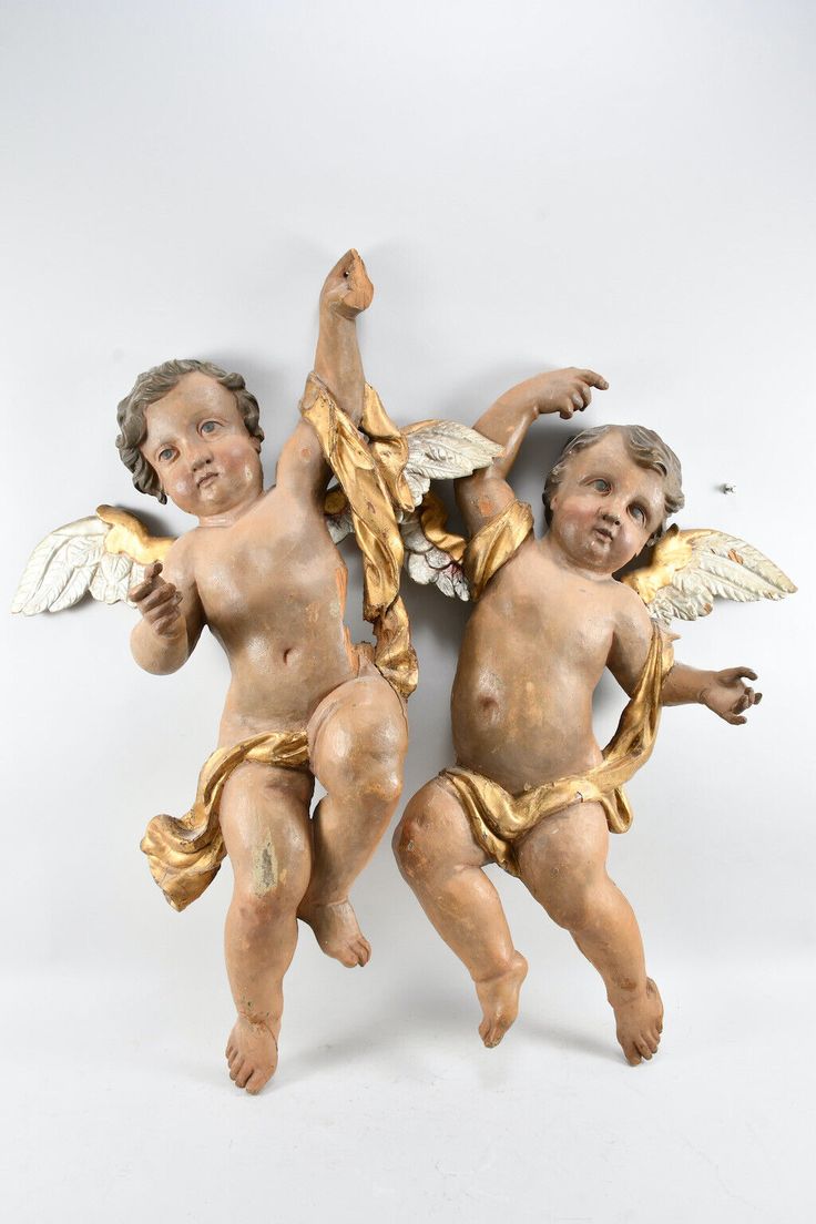 two cherubs with wings are posed on a white background and one has his arm outstretched