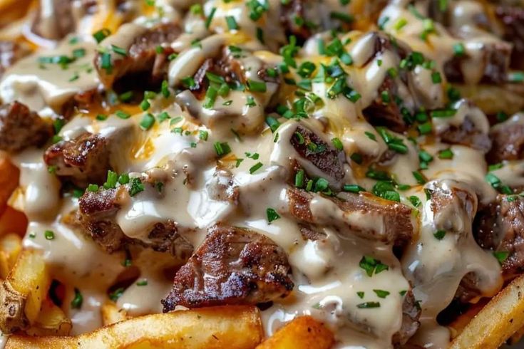 a close up of some french fries covered in cheese and gravy on a plate