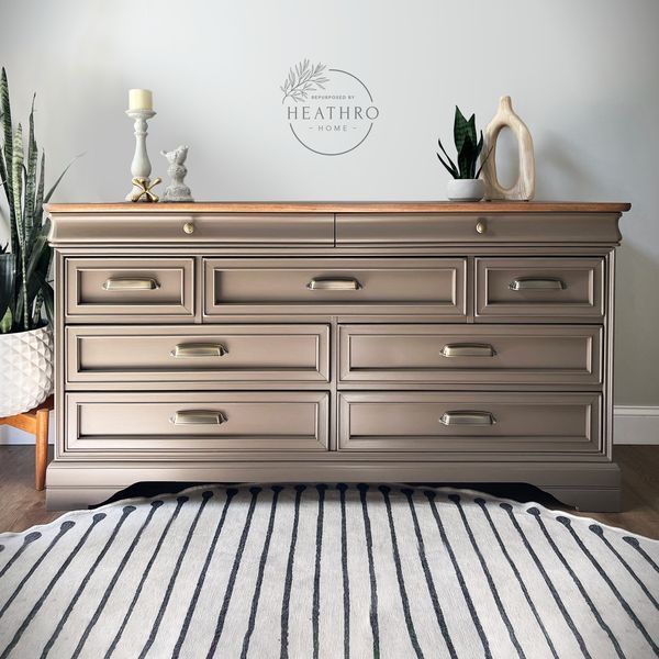 a large dresser with many drawers in a room next to a rug and potted plants