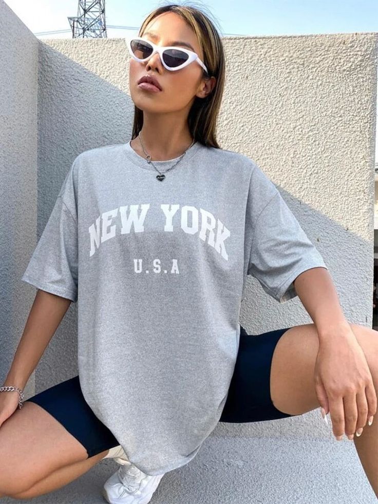 Elevate your summer wardrobe with our Retro NYC Letter Print T-Shirt. Made with breathable and durable cotton broadcloth, its classic O-neck collar and short sleeves offer both comfort and style. The retro-inspired print adds a nostalgic touch, perfect for those who appreciate vintage aesthetics. Effortlessly achieve a casual urban look while strolling through the city or hanging out with friends. Designed by Thekittenpark Cotton Short Sleeve T-shirt For Leisure, Leisure Crew Neck T-shirt With Letter Print, Gray Slogan Top For Summer, Summer T-shirt With Logo Print, Summer Gray T-shirt With Slogan, Summer College T-shirt With Screen Print, Summer Gray Cotton T-shirt, Summer College Tops With Logo Print, Gray Short Sleeve T-shirt With Letter Print