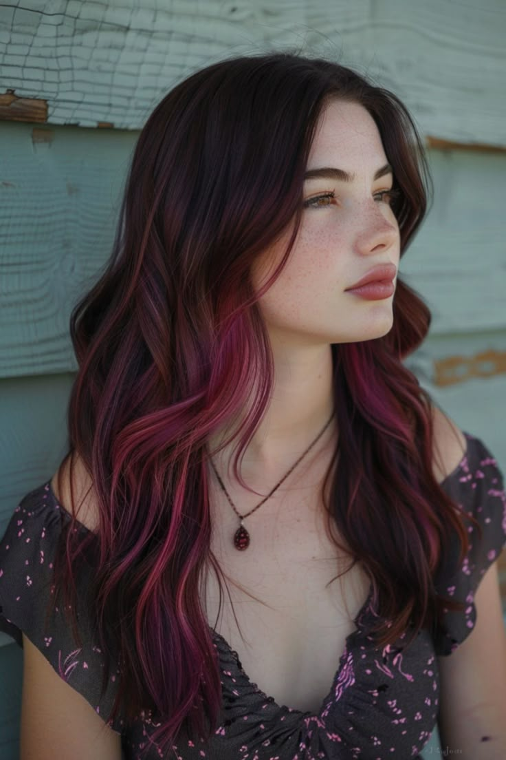 A young woman with shoulder-length ombre hair blending from dark brown to vibrant purple, looking thoughtfully to the side against a faded wooden backdrop. Highlight Colours For Brown Hair, Haircolor Ideas For Brown Skin Tone, Dark Red On Brown Hair, Brown And Coloured Hair, Vibrant Hair Color Ideas Brunettes, Dark Pink Hair Highlights, Colour Highlights Brown Hair, Dark Red Pink Hair, Red With Brown Hair