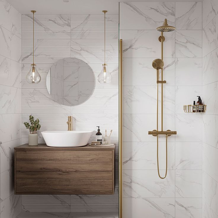 a bathroom with marble walls and flooring, gold faucet, mirror, sink, and shower head