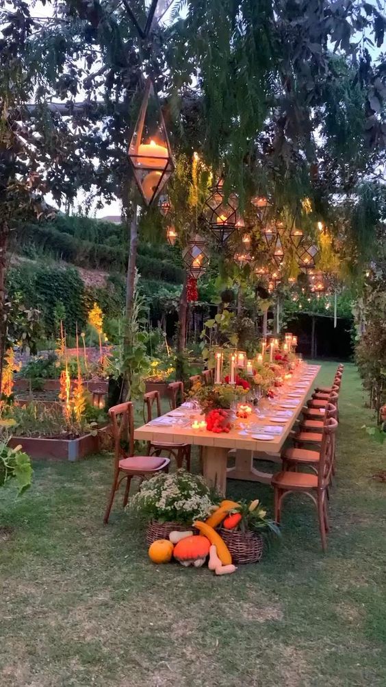 an outdoor dining table surrounded by vegetables and lights