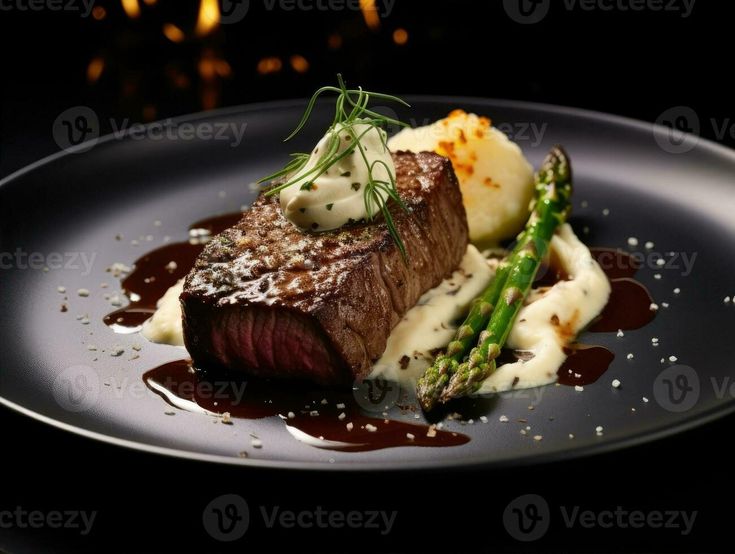 a piece of steak with asparagus and mashed potatoes on a black plate