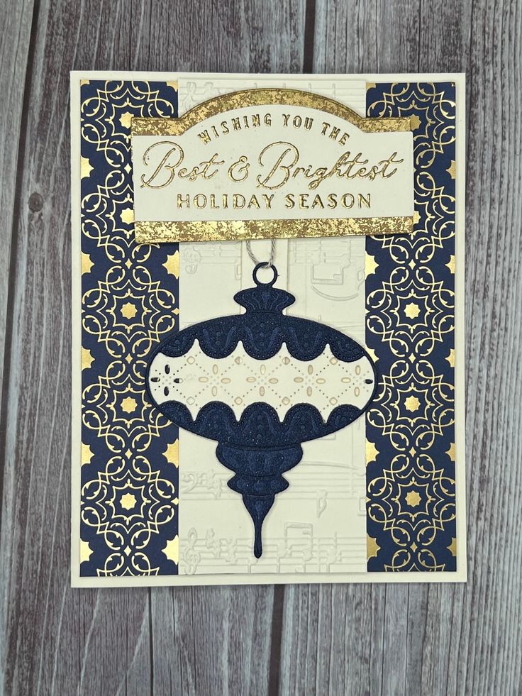 a christmas card with an ornament hanging from it's side on a wooden surface