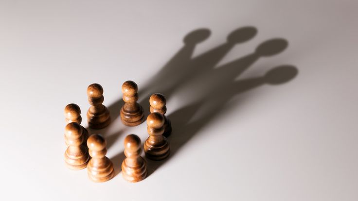 wooden chess pieces arranged in the shape of a man's shadow