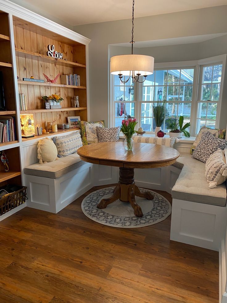 a dining room table and bench with built in bookshelves