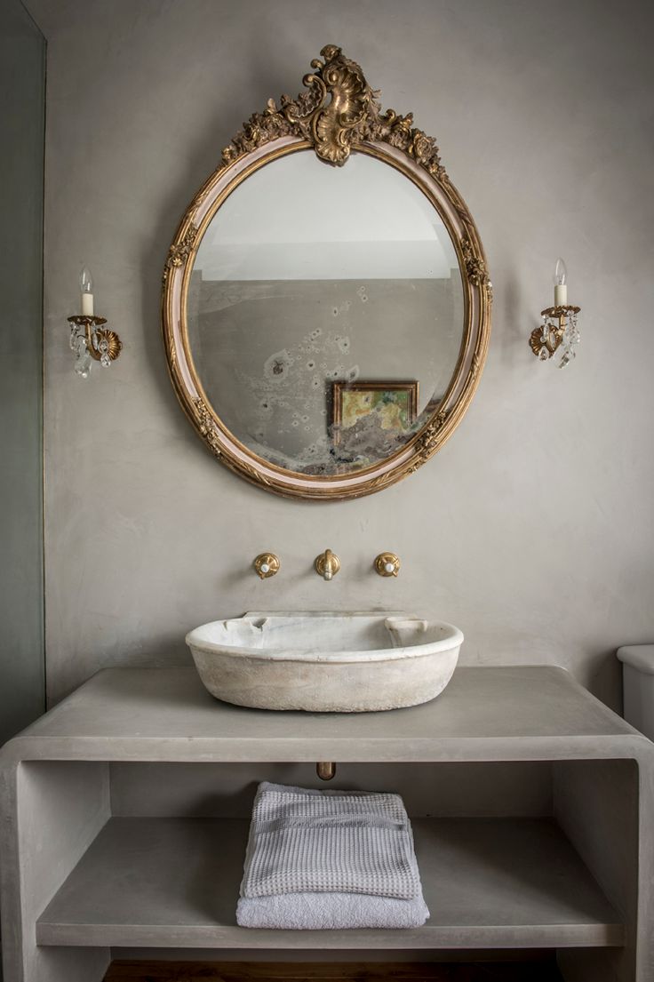 a white sink sitting under a round mirror