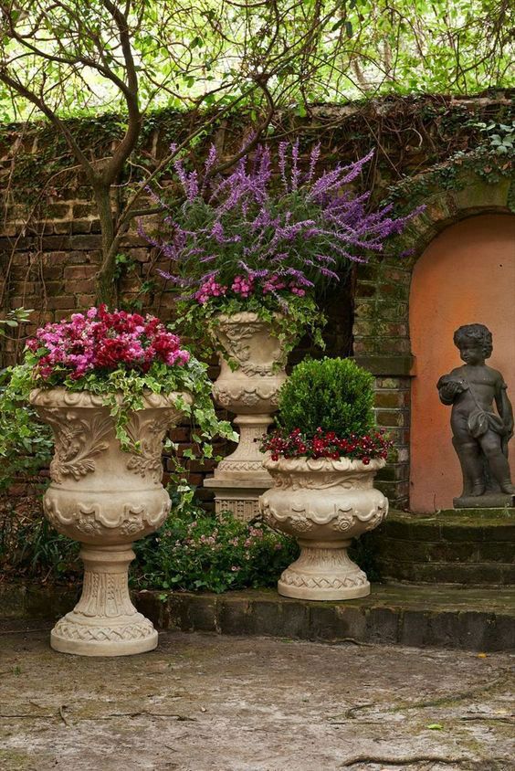 three large vases with flowers in them sitting next to a building