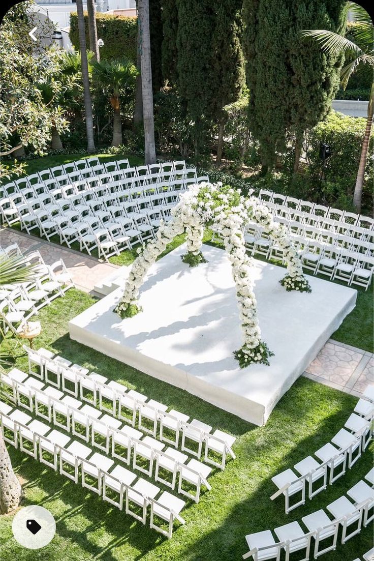 an outdoor ceremony setup with white chairs and flowers