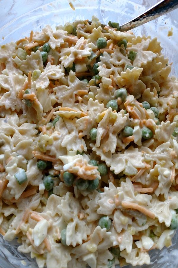 a glass bowl filled with pasta and peas