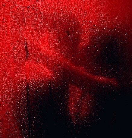 a red wall with water drops on it and a person's face in the background