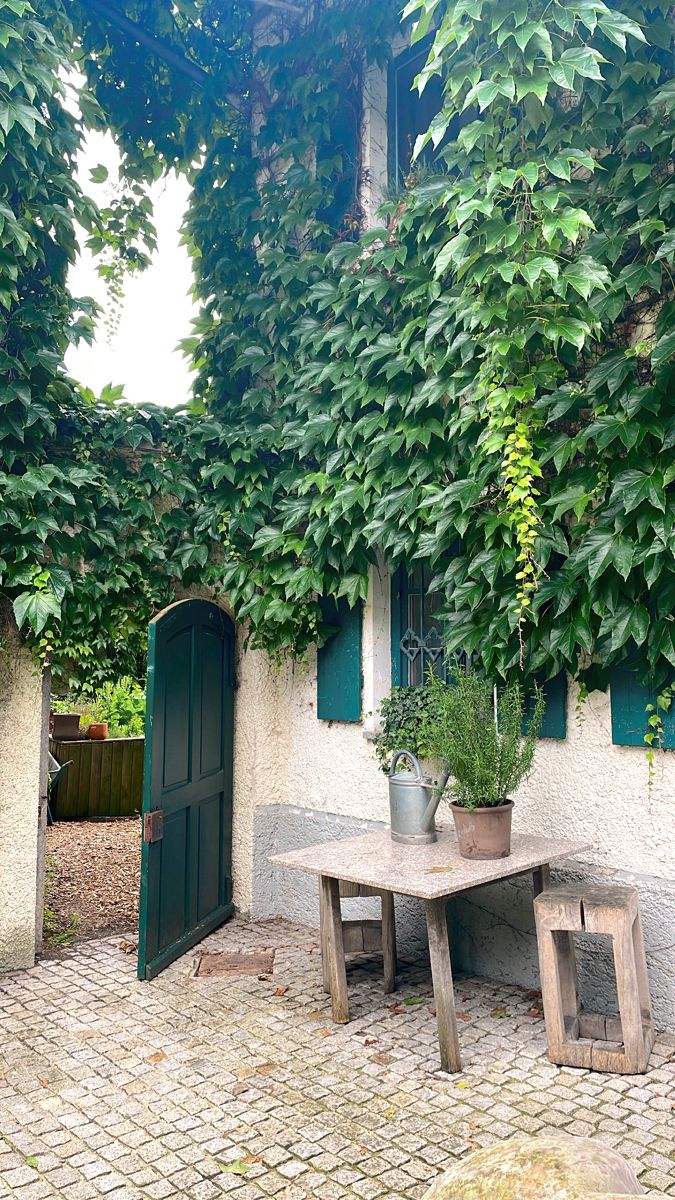 an outdoor table and bench in front of a house with ivy growing on the walls