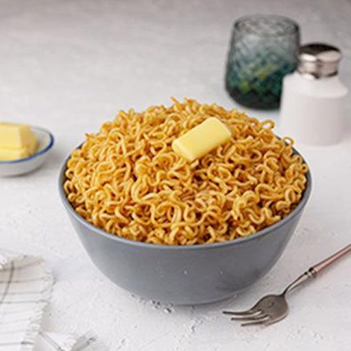 a bowl filled with noodles and butter on top of a white table next to utensils