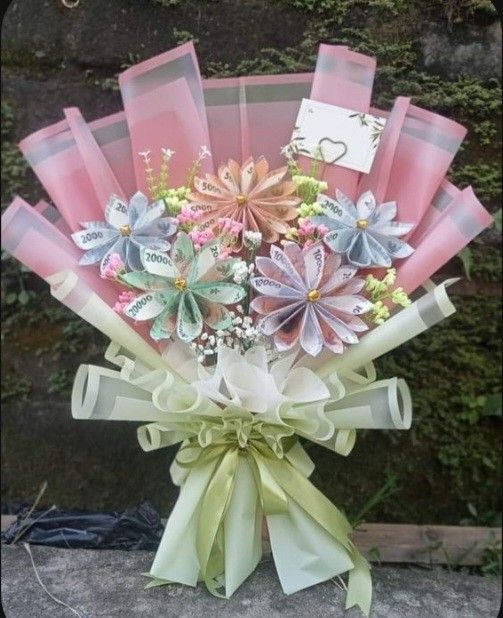 a bouquet of flowers is wrapped in pink and green ribbon with a name tag on it