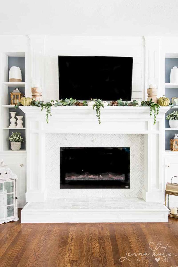 the fireplace is decorated with greenery and white mantles, along with a flat screen tv