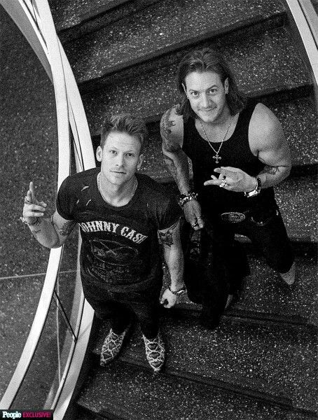 black and white photograph of two men sitting on an escalator, one pointing at the camera