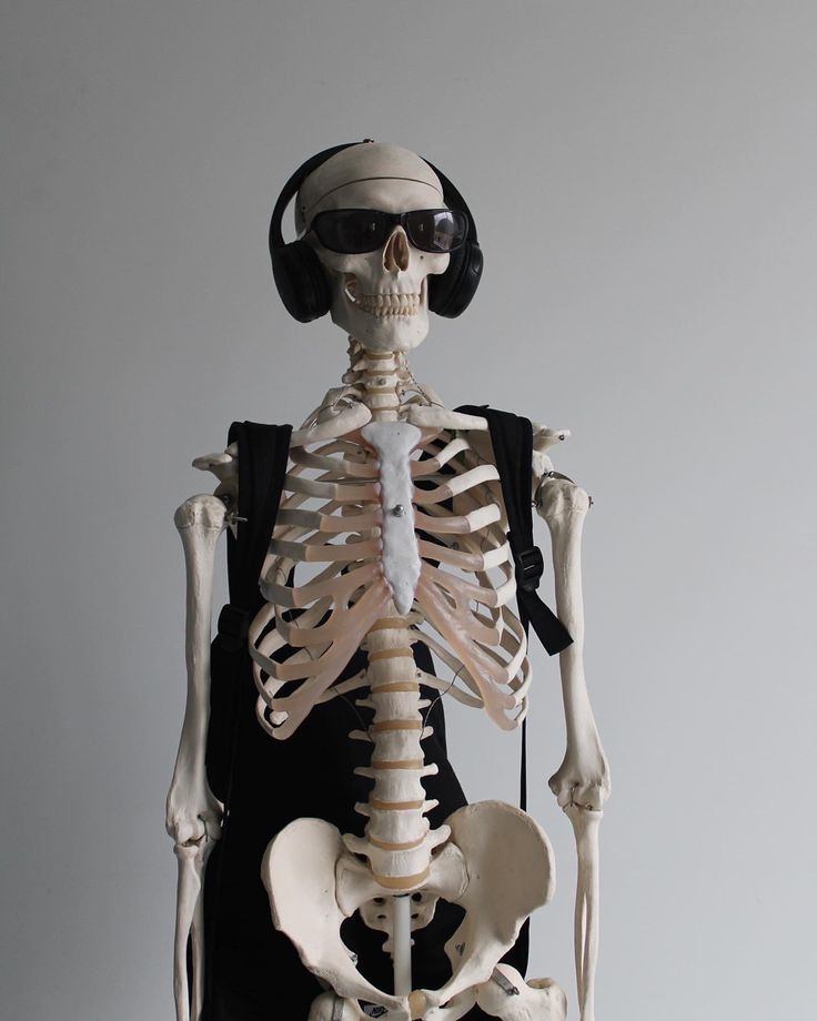 a skeleton with headphones on it's ears and wearing a black shirt is standing in front of a white background