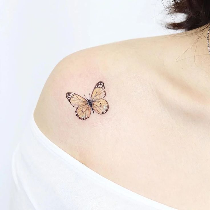 a woman's shoulder with a small butterfly tattoo on the left side of her upper arm