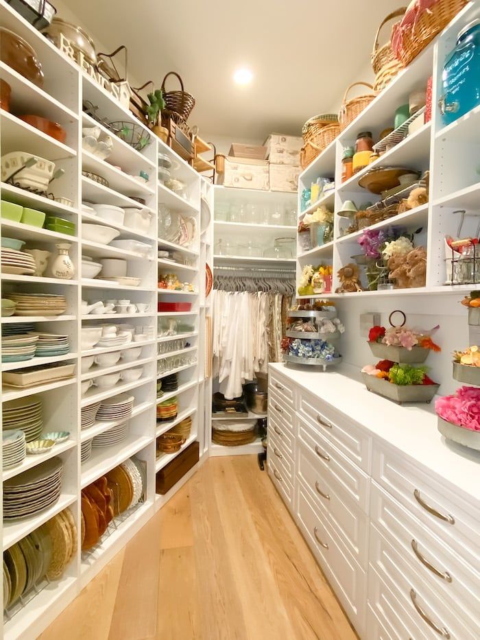 a walk in closet filled with lots of white shelves and baskets on top of them