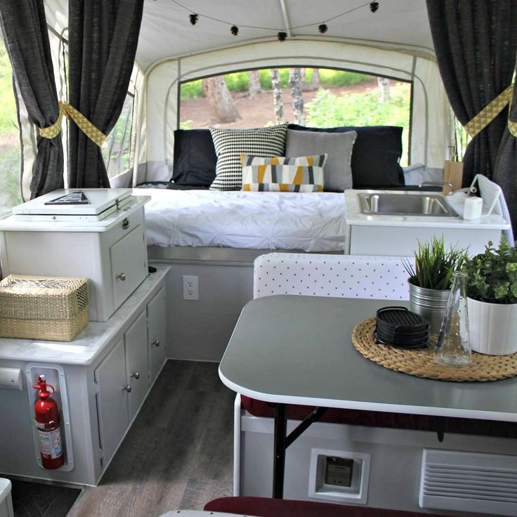 the inside of a camper with a bed, sink and stove top oven in it