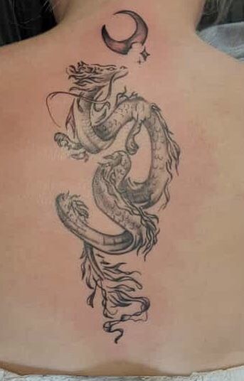 a woman's back with a tattoo design on her body and a dragon in the middle