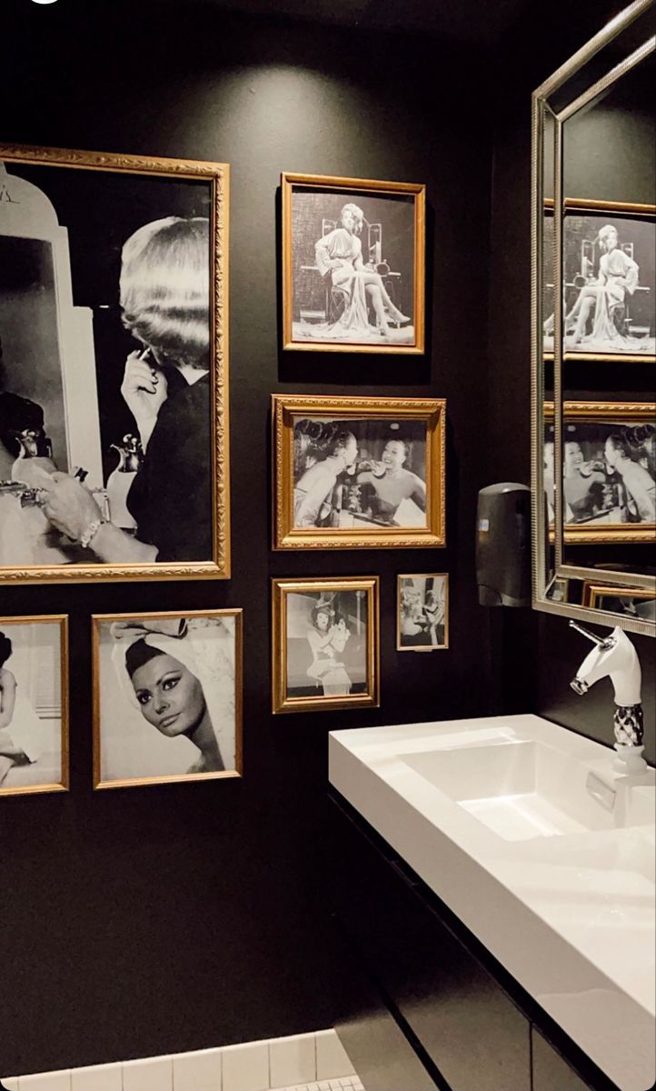 a bathroom with black walls and pictures on the wall