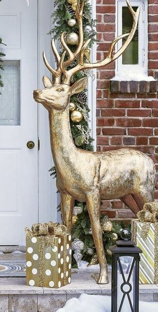 a gold deer statue next to presents in front of a house